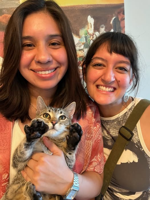 Happy adopter holding a tabby cat with friend