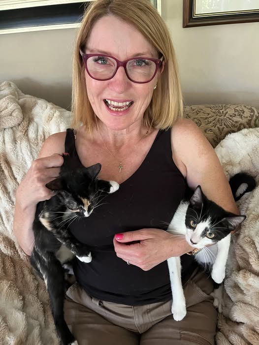 Woman smiling with two tuxedo kittens on her lap